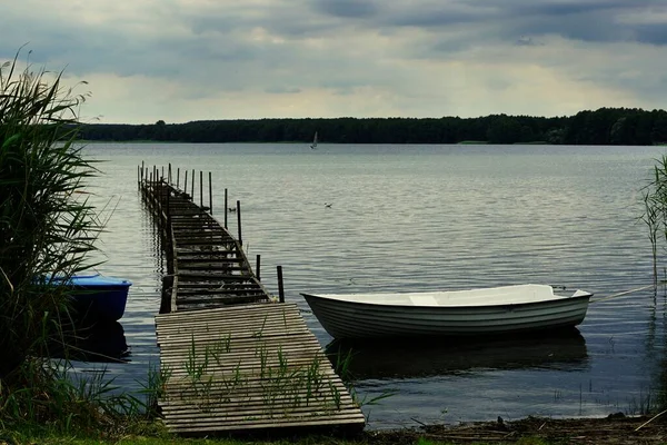 Beautiful shot of an old pier and a boat next to it in the lake Miedwie, Stargard, Poland. — стокове фото