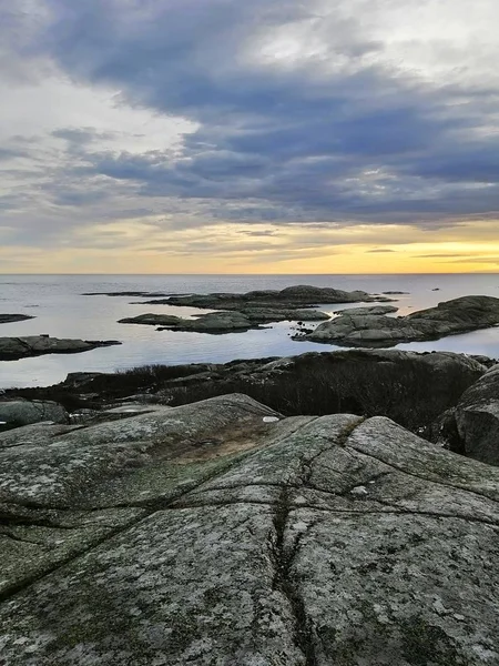 Verticaal beeld van rotsen omringd door de zee tijdens de zonsondergang in Rakke in Noorwegen — Stockfoto