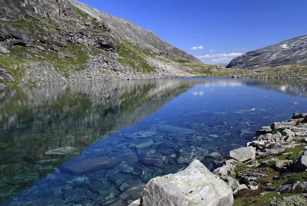 Lagoa soada por montanhas sob um céu azul — Fotografia de Stock