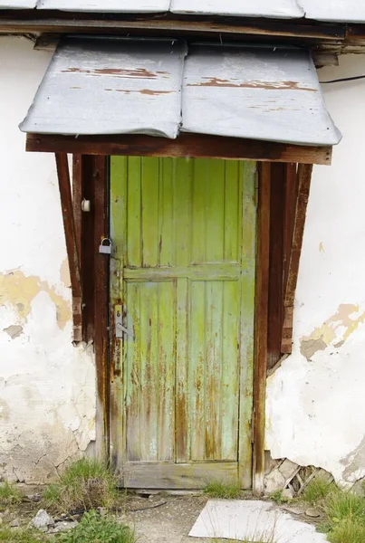 Vertical shot of an old green door on an abandoned building — Stock Photo, Image