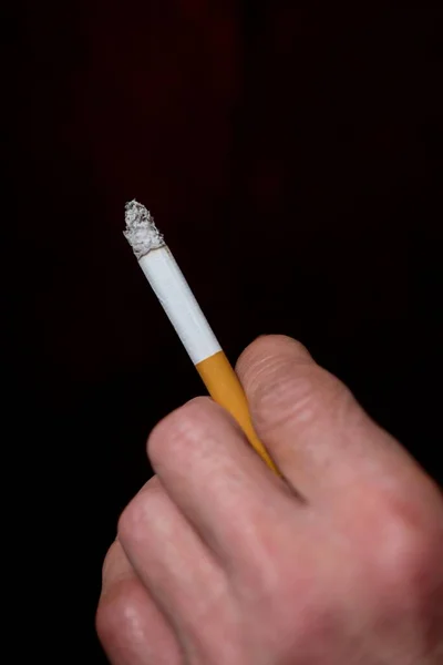Mužská ruka drží cigaretu s černým pozadím — Stock fotografie