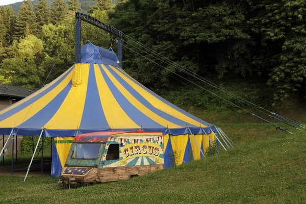 Kleurrijke blauwe en gele kleine circustent opgezet tussen de bomen op het gras — Stockfoto