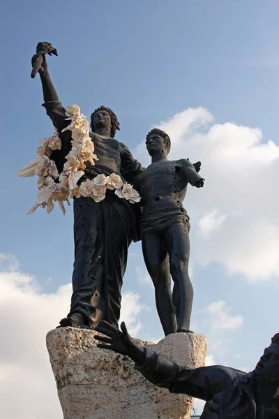 Vertical shot of a statue of two men next to each other under a blue sky — Stock Photo, Image