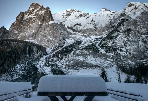 Parque com uma mesa coberta de neve rodeada por altas montanhas cobertas de neve rochosas nas Dolomitas — Fotografia de Stock
