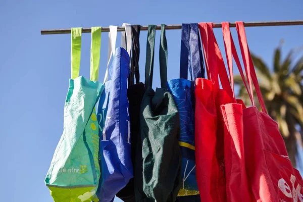 Baixo ângulo tiro de colorido eco-friendly sacos de pano reutilizáveis pendurados em um pólo - nenhum conceito de plástico — Fotografia de Stock