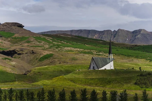 Церковь на травянистом холме вдалеке под облачным небом — стоковое фото