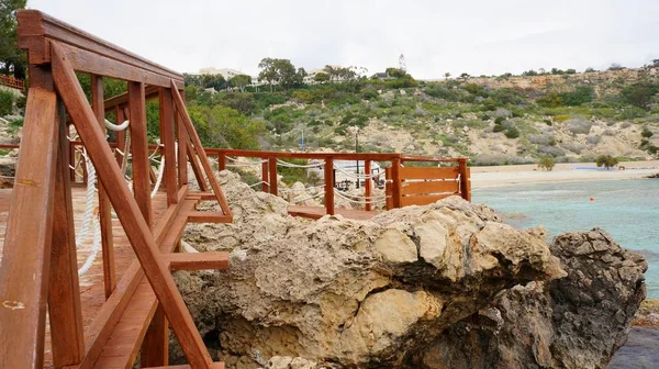 Trä brygga nära havet omgiven av stenar under den blå himlen — Stockfoto