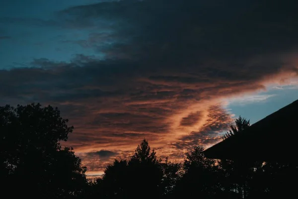 Krásná soumračná obloha se siluetami stromů a střechou — Stock fotografie