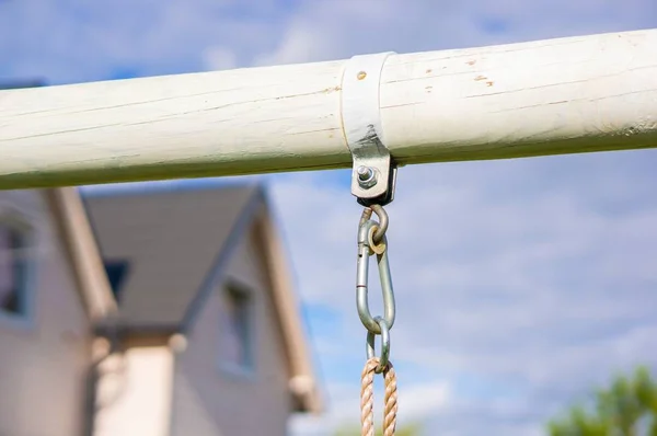 Appendino in metallo su un blocco di legno con una casa sullo sfondo in una giornata di sole — Foto Stock