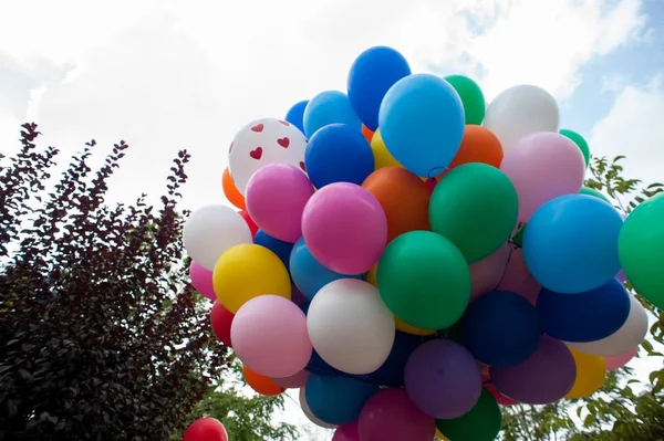 Bild von bunten Luftballons umgeben von Bäumen unter dem Sonnenlicht und einem bewölkten Himmel — Stockfoto