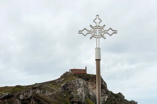 Hermosa vista del edificio sobre el acantilado con una cruz de metal en el primer piso de Bermeo. — Foto de Stock