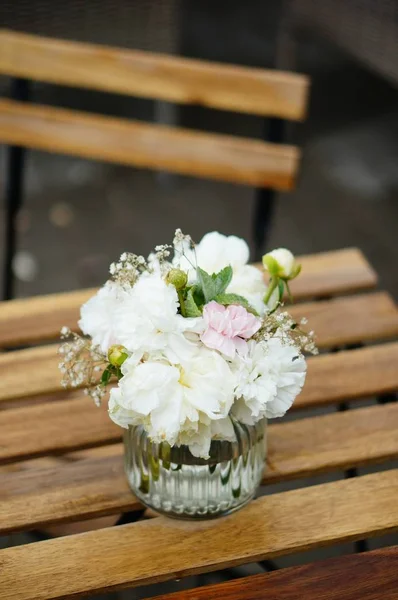 Beautiful shot of white flowers in a glass vase on a wooden table — Stock Photo, Image