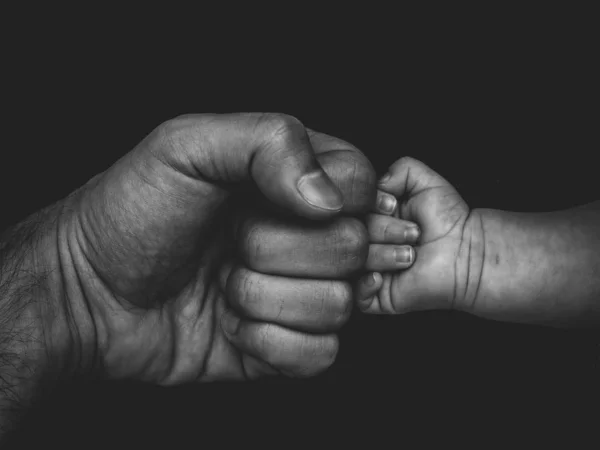 Foto a gran escala de los puños del hombre y del bebé juntos —  Fotos de Stock