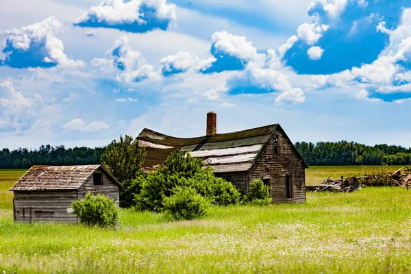 Pequena casa de madeira no prado verde sob o céu azul nublado — Fotografia de Stock