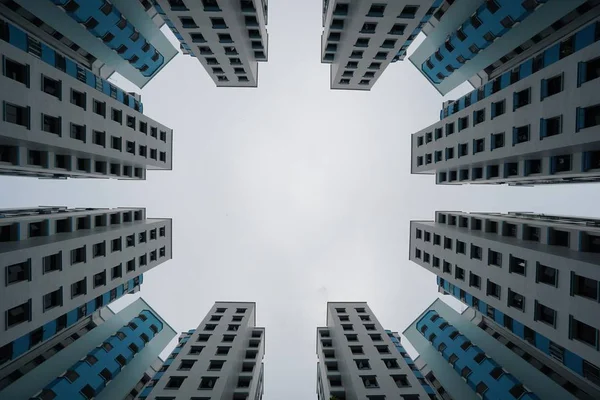 Niski Kąt Widzenia Błękitnych Białych Nowoczesnych Budynków Pod Zachmurzonym Niebem — Zdjęcie stockowe