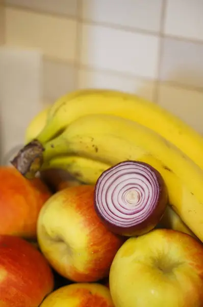 Verticaal schot bananen en appels met een ui op tafel in de keuken — Stockfoto