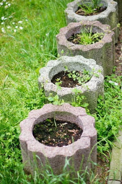 Κάθετη βολή από πέτρινες γλάστρες στο πράσινο γρασίδι — Φωτογραφία Αρχείου