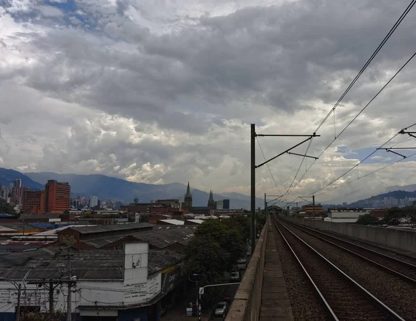 Çok bulutlu bir günde gökyüzüne ve şehre bakan bir tren rayından geniş açı. — Stok fotoğraf