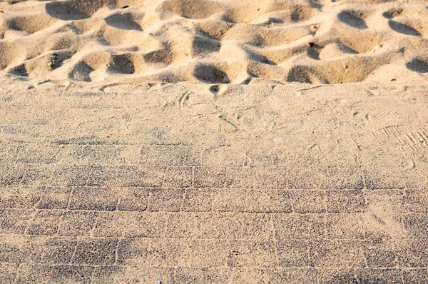 Encerramento tiro de uma calçada perto da areia da praia em um dia ensolarado — Fotografia de Stock