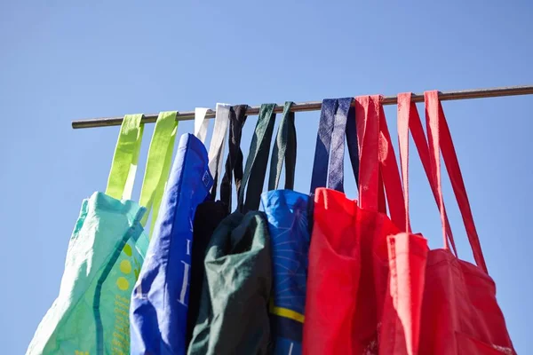 Captura de ángulo bajo de coloridas bolsas de tela reutilizables respetuosas con el medio ambiente colgadas en un poste, sin concepto de plástico —  Fotos de Stock