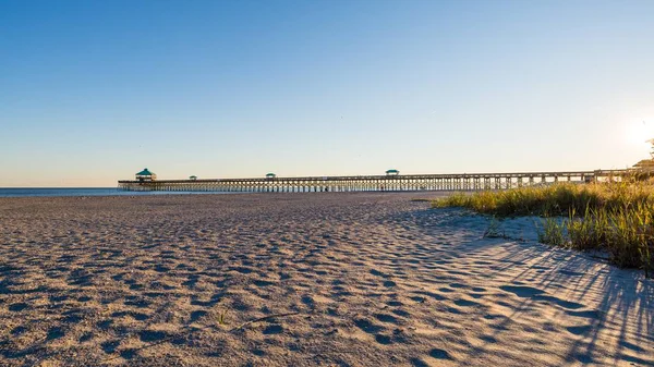 stock image A beautiful shot of an empty beach shore with a pathway over the water under a blue sky