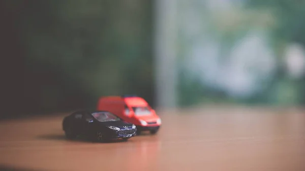 Επιλεκτική φωτογραφία εστίαση ενός σκούρο μπλε παιχνίδι αυτοκίνητο και ένα θολό κόκκινο παιχνίδι van στο τραπέζι — Φωτογραφία Αρχείου