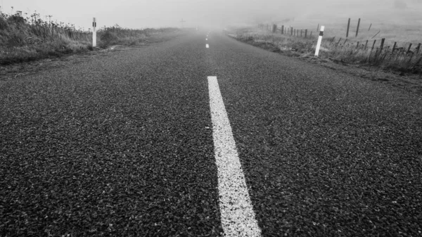 Šedivý Záběr Silnice Uprostřed Polí Mlhavým Pozadím — Stock fotografie
