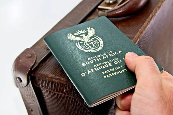 Homem segurando um passaporte africano em uma bagagem marrom — Fotografia de Stock