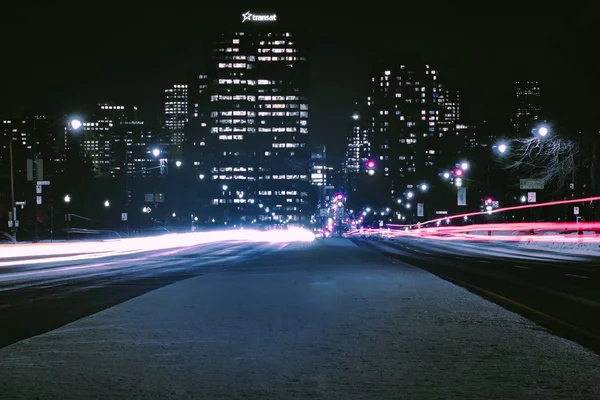 Cidade moderna com arranha-céus e carros passando à noite — Fotografia de Stock