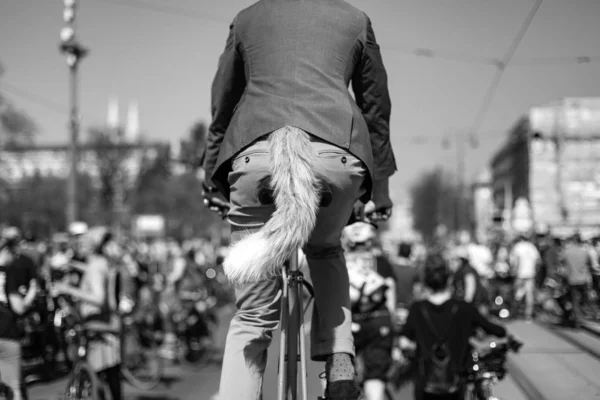 Zdjęcie w skali szarości osoby jeżdżącej na rowerze po ulicy z lisim ogonem — Zdjęcie stockowe