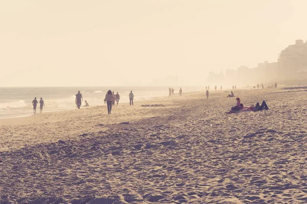 Берег моря с людьми, гуляющими в солнечный день — стоковое фото