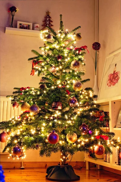 Árvore de Natal cuidadosamente decorada com luzes de corda e ornamentos únicos - conceito de Natal — Fotografia de Stock