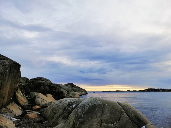 Havet omgivet av klippor under en molnig himmel under solnedgången i Stavern i Norge — Stockfoto