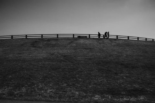 Baixo ângulo tiro de caminhantes ao longo das grades em uma colina em monocromático — Fotografia de Stock
