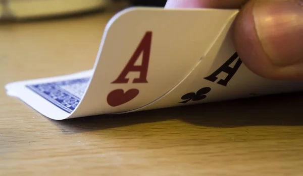 Tenir des cartes d'as noires et rouges sur la table sous les lumières sur un fond flou. — Photo