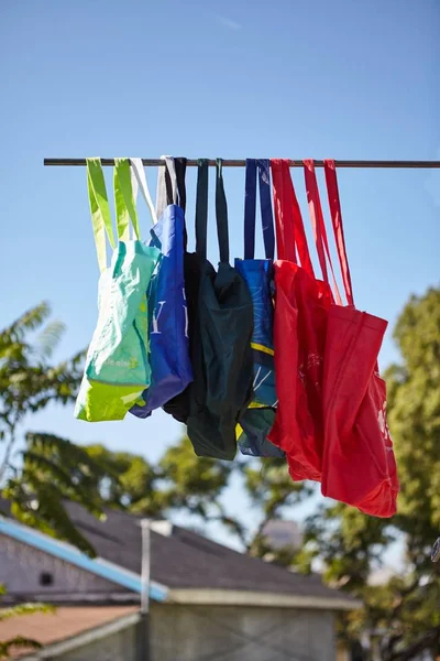 Baixo ângulo tiro de colorido eco-friendly sacos de pano reutilizáveis pendurados em um pólo - nenhum conceito de plástico — Fotografia de Stock