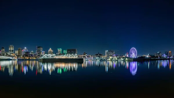 Tiro panorâmico de uma cidade moderna com arranha-céus e uma roda gigante com a sua reflexão — Fotografia de Stock