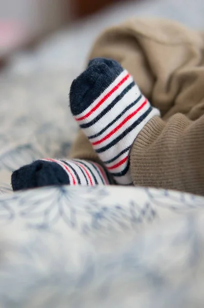 Beautiful shot of the cute baby feet wearing white socks on the bed — Stock Photo, Image