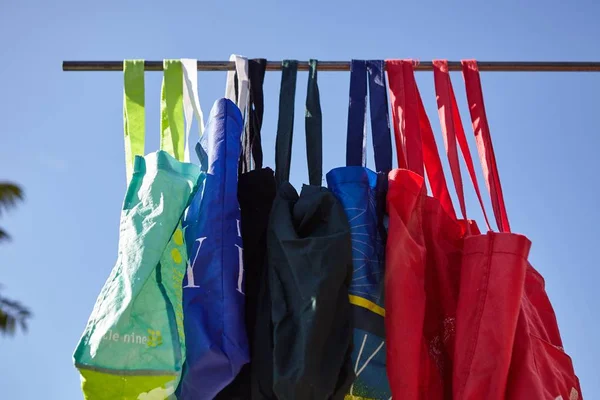 Baixo ângulo tiro de colorido eco-friendly sacos de pano reutilizáveis pendurados em um pólo - nenhum conceito de plástico — Fotografia de Stock