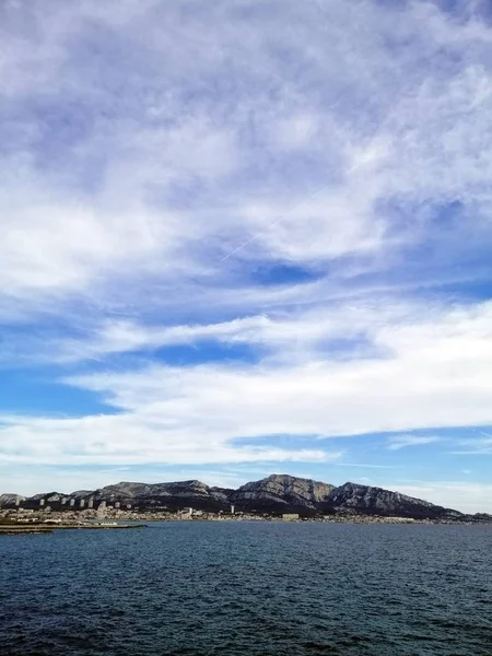 Verticaal beeld van de zee omringd door rotsen onder een bewolkte lucht in Marseille in Frankrijk — Stockfoto