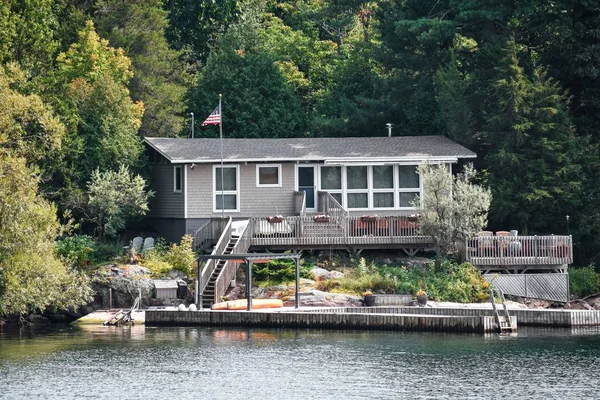 Haus am Fluss, umgeben von einem Wald, tagsüber im Sonnenlicht — Stockfoto