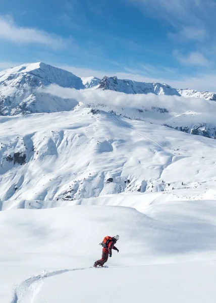 Вертикальный снимок мужчины, катающегося на сноуборде в заснеженных горах — стоковое фото