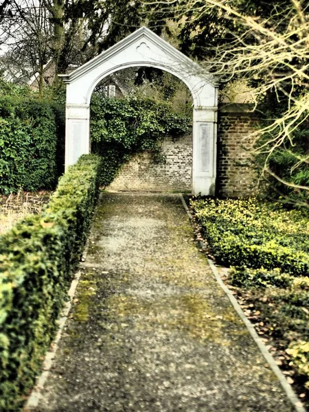 Vertikale Aufnahme des Eingangs eines Parks, umgeben von Gras und Bäumen — Stockfoto