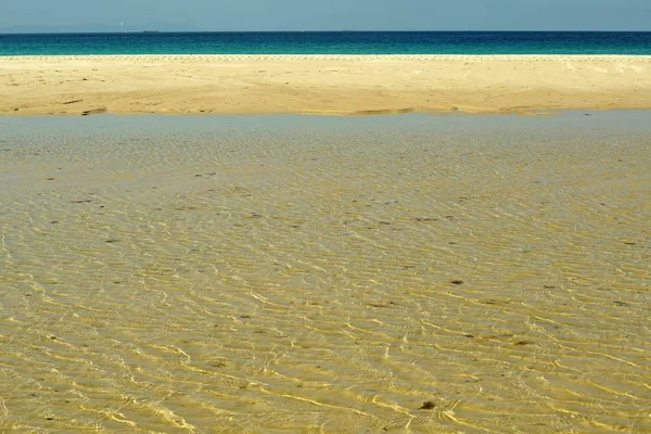 Hermoso tiro de la superficie del agua sobre una playa de arena en Tarifa, España. — Foto de Stock