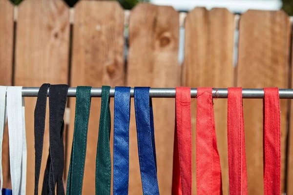 Lote de colorido eco-friendly sacos de pano reutilizáveis pendurados em um poste perto de uma cerca de madeira — Fotografia de Stock