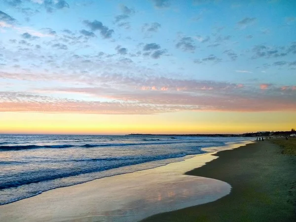Снимок спокойных морских волн, омывающих пляж Кадиса, Испания, во время заката — стоковое фото