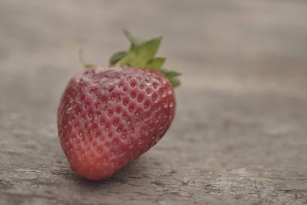 Tournure de fermeture au foyer d'une fraise fraîche rouge savoureuse sur une surface en bois — Photo