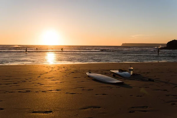 遠くの人と一緒に海岸沿いのサーフボードの美しいショット — ストック写真