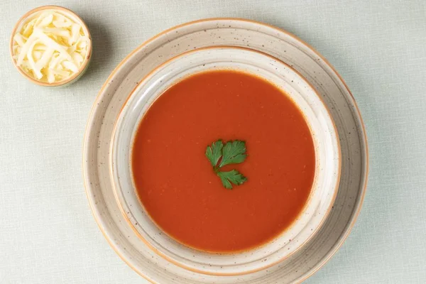 Tiro suspenso da sopa de tomate com verde no topo — Fotografia de Stock