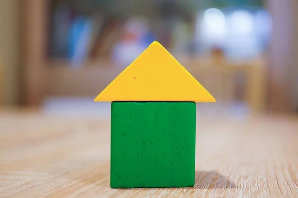 Kleine houten gele driehoek op een groene kubus op de tafel onder de lampen — Stockfoto